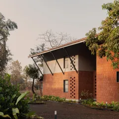 An exterior view of Maison Rouge, a family home built on ancestral land in the Konkan belt. We balanced contemporary planning with vernacular building traditions, using locally sourced laterite stone to create a structure that feels rooted in its place and history.