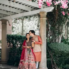 A sweet, romantic moment under a bougainvillea-covered arch. The groom's gentle kiss on the bride's head is a perfect, tender detail.