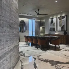 A view of the dining space in a contemporary Mumbai home, where a striking marble floor creates a canvas for modern art and furniture. The textured wall and organically shaped mirror add layers of visual interest and sophistication.