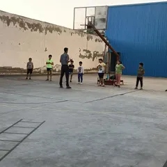 I am explaining a drill to a group of young basketball players. My coaching method involves direct instruction and breaking down plays to help build a strong foundation in the sport.