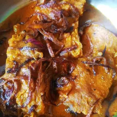 This is my take on the traditional Katlar Kalia, a rich fish curry I remember from childhood wedding feasts. The fried carp is simmered in a thick, spicy gravy, making it a truly decadent dish for special occasions.
