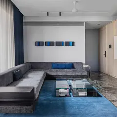 The custom L-shaped sofa in 'A Wedged Haus' includes an integrated side table. This piece was designed to fit the specific dimensions of the living room, demonstrating how furniture can be tailored to the architecture.