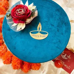 Our round velvet boxes are perfect for premium gifting. This beautiful teal box is adorned with a flower and a golden emblem, making it a cherished keepsake.