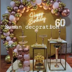 An elegant setup for a 60th birthday celebration. This decoration features a rose gold, pink, and gold color palette, a sequin backdrop, and a full dessert table display.