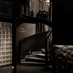 The iconic spiral staircase at Lair, crafted from reflective stainless steel, acts as a sculptural centerpiece. It connects the three distinct levels of the speakeasy, its distorted reflections adding to the space's disorienting and clandestine atmosphere.