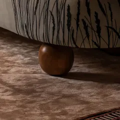 Every detail is considered, right down to the feet of the furniture. Here, the custom-printed fabric of the sculptural armchair meets a solid wood bun foot, resting on a plush, textured rug. This interplay of materials is central to our design approach.