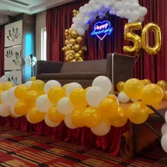 A classic and elegant setup for a 50th anniversary celebration. The stage features a golden and white balloon arch, a 'Happy Anniversary' neon sign, and a large '50' foil balloon, creating a perfect photo opportunity.