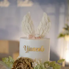 A close-up of a beautiful custom cake for a baptism. The delicate angel wings and floral details show the artistry that goes into our dessert offerings.