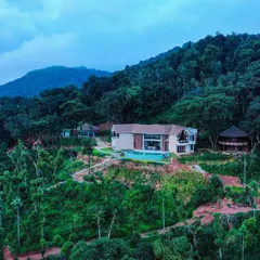 This modern home is nestled amidst the dense greenery of the hills. The design uses a combination of natural stone, wood, and large glass panels to create a structure that feels like a natural extension of the mountain itself.