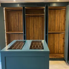 For this spacious walk-in closet, we built a custom central island in a striking teal PU finish. The island features glass-top display drawers, perfect for organizing watches, ties, and accessories, adding another layer of functionality and style.