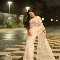 The model's pose here beautifully shows the flow and detail of the sheer saree against the rainy, urban backdrop. This is a great example of a creative portrait session in challenging weather.