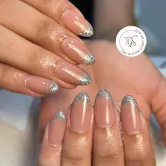 A glamorous twist on the French manicure. This design features a classic nude base with sparkling silver glitter tips for a touch of party-ready glam.