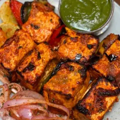 You can't go wrong with a classic Paneer Tikka. I marinate soft cubes of paneer in a blend of yogurt and spices, then grill them with peppers and onions until they have the perfect char. It's served with our signature mint chutney and sliced onions.