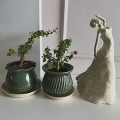 The finished sculpture of the dancing woman, now fired and glazed, standing next to two of my small planters.