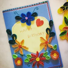 A student's finished paper quilling birthday card. This craft project teaches children patience and precision as they roll and shape paper strips into beautiful floral designs.