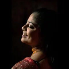 A close-up profile shot of the bride during her engagement. The soft side lighting beautifully illuminates her happy expression and traditional nath, creating a timeless and elegant portrait.