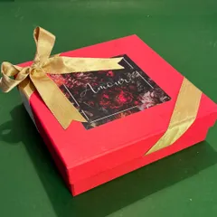 The elegant packaging for my Rakhi floral candle. The vibrant red box with a floral motif and gold ribbon makes it a beautiful and thoughtful gift for your brother and sister-in-law.