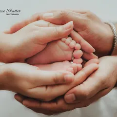 A family's hands cradling the tiniest feet. This powerful image symbolizes the love and protection surrounding a new baby.
