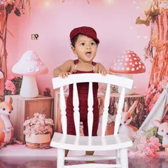 A baby boy peeks over a white chair with a look of surprise in this enchanted forest setting. The warm lighting and woodland creatures create a cozy and adventurous atmosphere.
