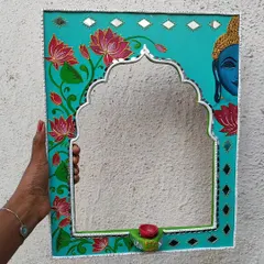A unique Jharokha mirror that combines the Rajasthani frame with a serene, hand painted Buddha and lotus flowers. It also includes a small holder for a candle or diya.