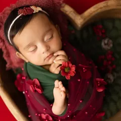 This portrait captures the peaceful sleep of a newborn, swaddled in festive red and green. The heart-shaped wooden bowl is one of the many props I have in my Navi Mumbai studio to create unique setups.