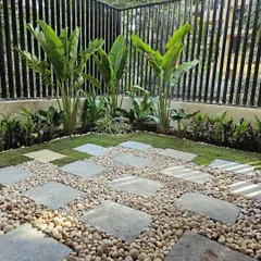 I designed this modern backyard corner to be super low maintenance but high on style. The combination of large stone pavers, smooth river pebbles, and tall Traveller's Palms creates a clean, tropical feel that's perfect for relaxing.