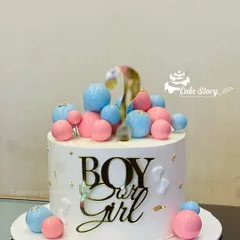 A classic 'Boy or Girl?' gender reveal cake. The clean white cake is decorated with pink and blue spheres and a big golden question mark.