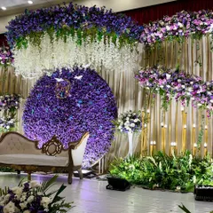 For this monsoon wedding reception, we designed a romantic stage drenched in shades of purple. A massive circular backdrop of purple chrysanthemums, paired with hanging white wisteria and lush greenery, creates a dreamy, immersive floral experience.