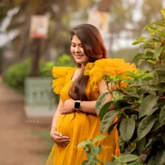 A candid moment captured during an outdoor shoot in a local park. The natural greenery provides a perfect backdrop for the bright yellow gown, and her smile is pure sunshine.