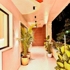 A view of a residential balcony at night. I used a combination of wall sconces and spotlights to create a warm and inviting outdoor space. The abundance of potted plants makes this long balcony feel like a private garden, perfect for relaxing in the evening.