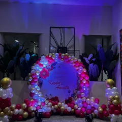 I can personalize your party backdrop with names or messages. This balloon ring was customized for Kevin and Aneeta's celebration, using a mix of pink, white, and gold balloons with spotlights.