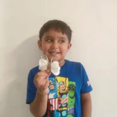 A young creator proudly holds up his finished butterfly craft, made from a toilet paper roll and paper wings. We love using everyday materials to show that art can be made from anything.