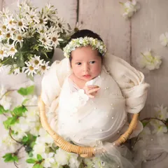 A basket of beauty. This awake baby girl is nestled among white flowers, creating a fresh and angelic portrait with a rustic touch.