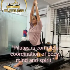 A client holds a powerful pose on the Reformer, demonstrating the complete coordination of body, mind, and spirit that Pilates cultivates.