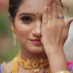 A creative pose showing one half of the bride's face, emphasizing the detailed eye makeup and the classic Chandrakor bindi. This is a perfect example of a natural yet captivating bridal look.