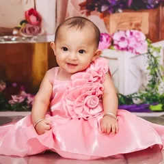 Dressed in a lovely pink gown, this baby girl's smile lights up the room. Sitter sessions are perfect for capturing these bright, engaging expressions.