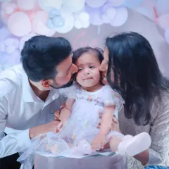 Surrounded by love. Parents give their little girl a kiss on each cheek during her birthday celebration.