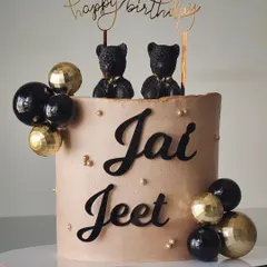 This cake for twin boys, Jai and Jeet, is modern and sophisticated. The smooth taupe buttercream is decorated with black and gold spheres and topped with two stylish bear figures.