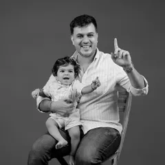 A proud father holds his son in this joyful black and white portrait. We aim to capture the special connection between each family member.