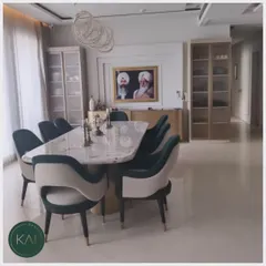 We crafted this dining area to exude refined grace. The centerpiece is a substantial marble-top dining table, surrounded by two-tone upholstered chairs in teal and cream, offering both exceptional comfort and a striking visual statement for memorable dinners.