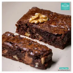 A close-up of our Walnut Brownie, cut to reveal the generous amount of walnuts and chocolate chunks baked inside. It's the ultimate comfort dessert.