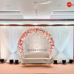 This dreamy ring ceremony setup features a circular floral arch with hanging glass baubles, creating a delicate and magical focal point behind the couple's seating.