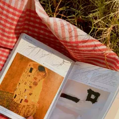 Reading a book on a picnic blanket, the pages glowing in the golden light of the setting sun.