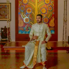 A full look at the off-white embroidered sherwani set. The gold-bordered sash adds a touch of traditional grandeur, while the tailored fit of the jacket keeps the silhouette modern.