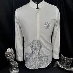 A bold statement in minimalist design. This white shirt features an abstract, linear portrait and a geometric floral motif, both embroidered in black. It is a piece of wearable art, perfect for the modern man.