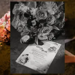 A detail shot in black and white, featuring the wedding rings on the invitation card next to the bridal bouquet. It's the little things that tell the big story.