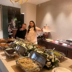 A happy client posing with me behind a lavish spread at a house party. My goal is to create food that becomes the most talked-about part of your celebration.