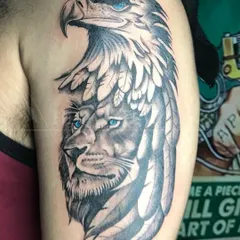 A powerful composite tattoo merging the faces of a lion and an eagle, both with striking blue eyes. This piece symbolizes strength, vision, and freedom.
