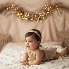 A real-life doll. Her squishy cheeks and big, sparkling eyes are just everything in this cozy, fairy-lit boho setup.