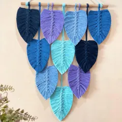 A close-up of the blue and purple leaf wall hanging. You can see the detailed knotting that forms the spine of each leaf and the soft, brushed-out texture of the cord.